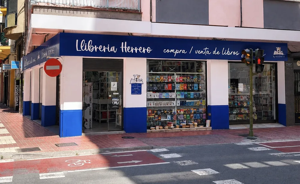 Fachada azul de Librería Herrero en la esquina del Carrer d'Herrero