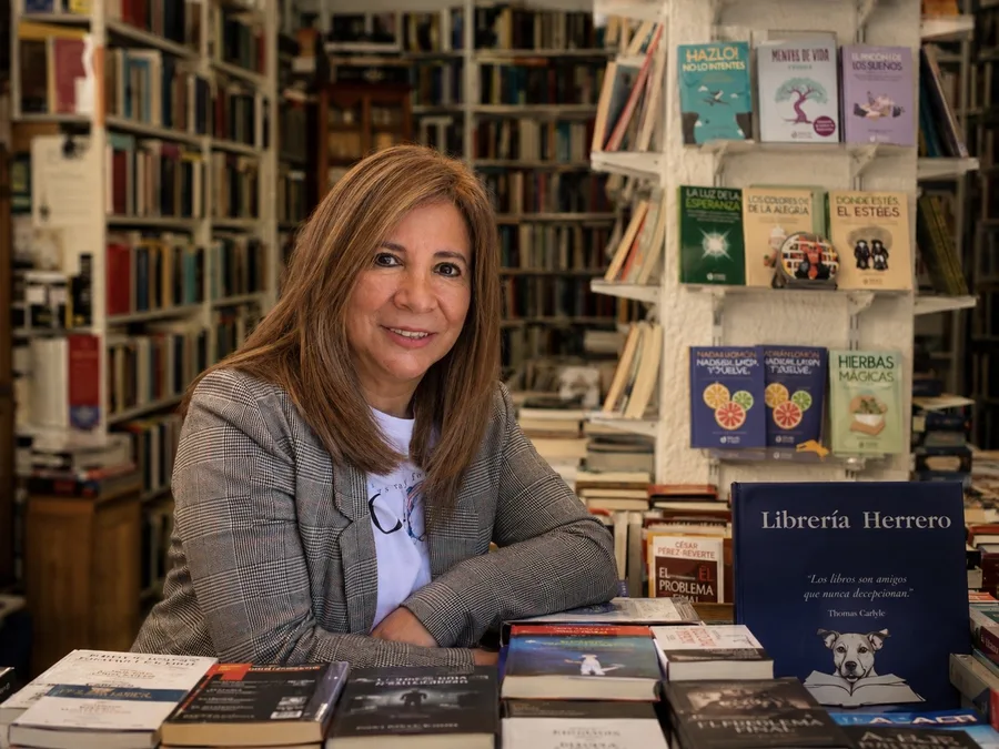 La dueña de Librería Herrero en el mostrador, rodeada de libros