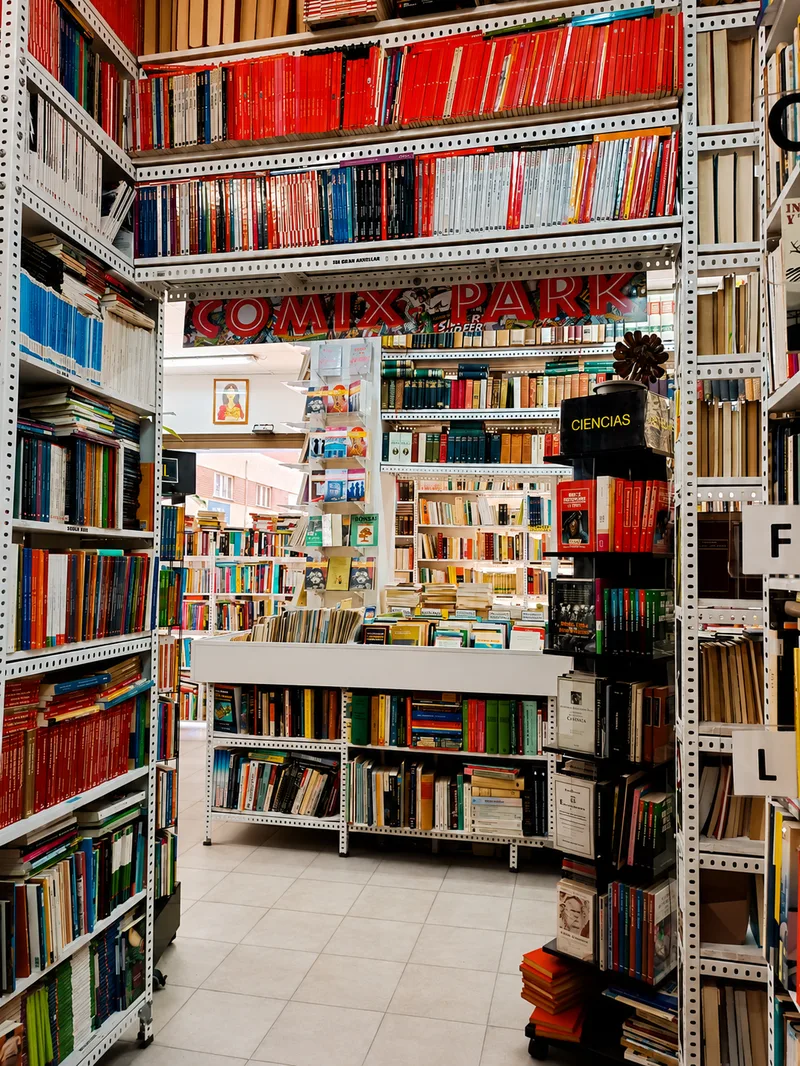 Pasillos con estanterías blancas repletas de libros de segunda mano